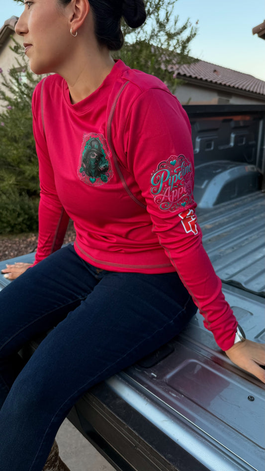 Woman wearing a bright pink long sleeve performance work shirt with graphic prints on the chest and sleeve.