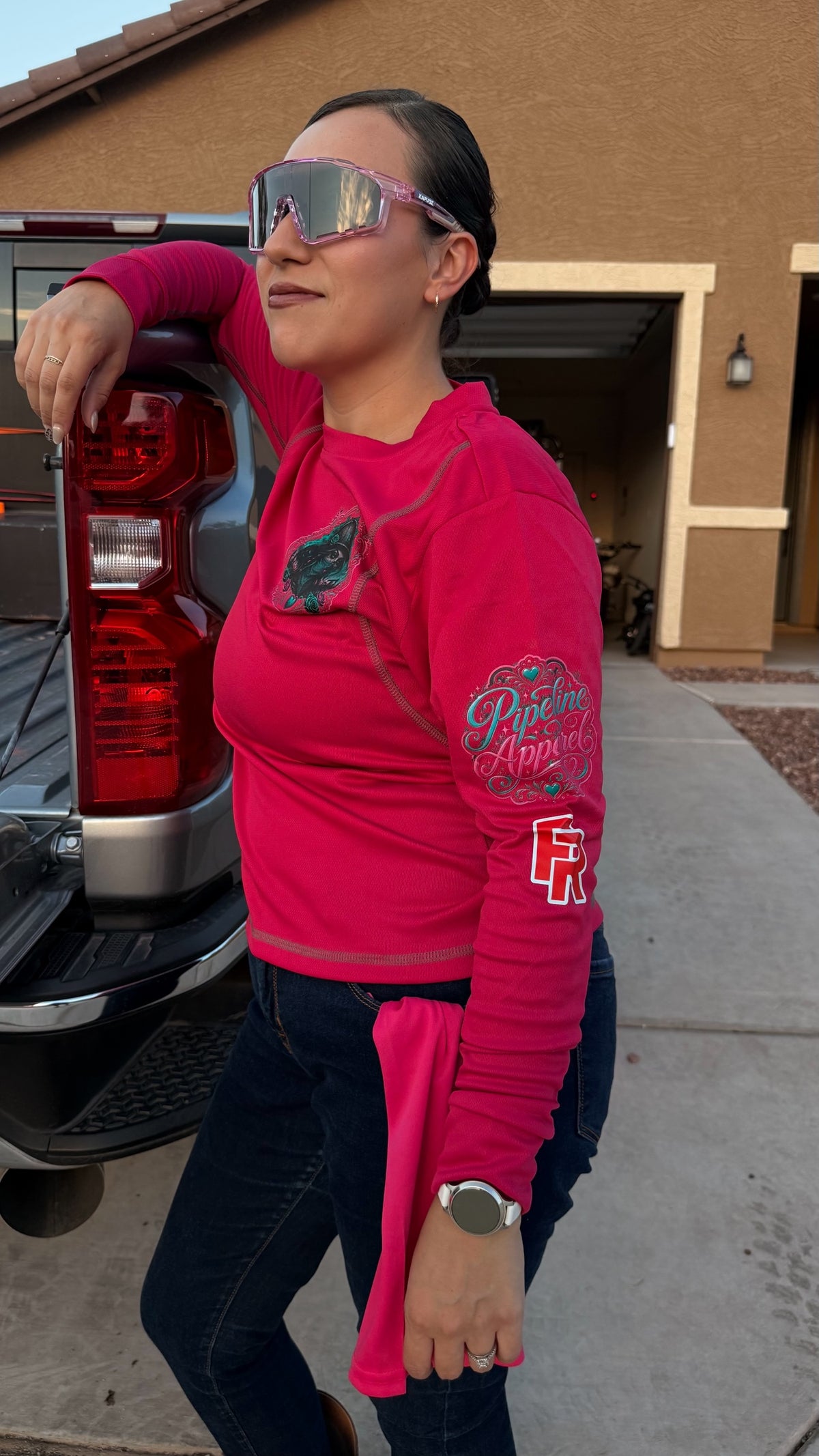 Woman wearing a hot pink long sleeve performance work shirt with graphic sleeve detailing and moisture-wicking fabric.